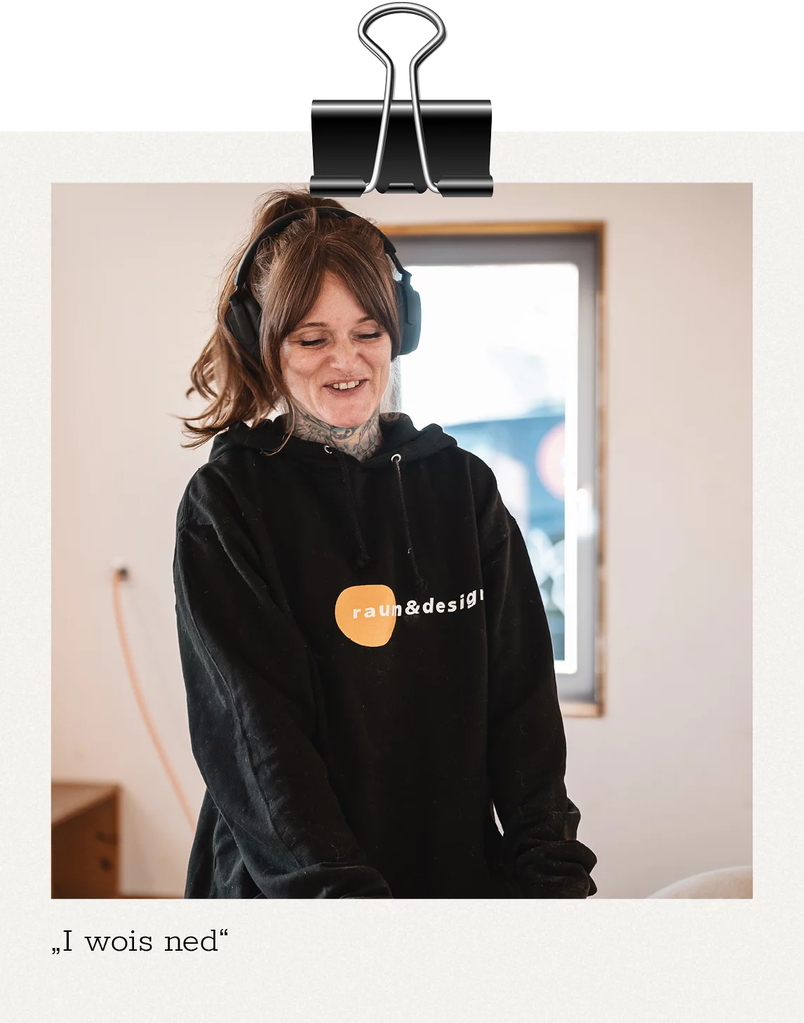 Unsere Story: Cora mit Kopfhörern lächelt beim Arbeiten mit dem Schleifgerät. Unter dem Bild steht "I wois ned"